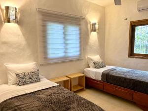 a small room with two beds and a window at Villa Las Malaguenas in Las Terrenas