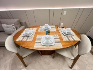 LK Centro 11 في بيلو هوريزونتي: طاولة خشبية عليها صحون وصحون بيضاء
