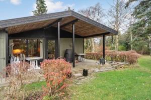 a cabin with a wooden deck in a yard at 8027-Kalvehave-Ulvsundvej-27 in Kalvehave