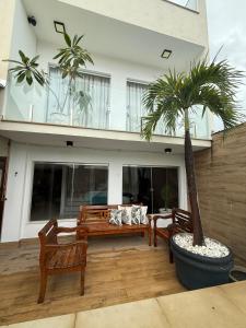 eine Terrasse mit Bänken und einer Palme vor einem Gebäude in der Unterkunft Bela casa em Guaratiba in Mato Alto