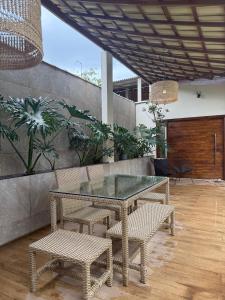 eine Terrasse mit einem Glastisch und 2 Stühlen in der Unterkunft Bela casa em Guaratiba in Mato Alto