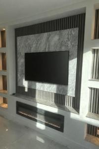 een flatscreen-tv aan een muur in een woonkamer bij Hendham Lodge in Manchester +5 foto's