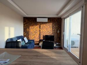 ein Wohnzimmer mit einer blauen Couch und einem Fernseher in der Unterkunft Comfortable apartment with sea view in Le Barcarès