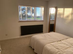 a white bedroom with a bed and two windows at Comfortable Homestay by Earith Lakes in Earith