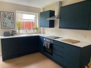a kitchen with blue cabinets and a sink at Comfortable Homestay by Earith Lakes in Earith +10 photos
