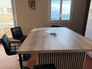 einen Holztisch mit Stühlen und eine Glasschüssel darauf in der Unterkunft Comfortable apartment with sea view in Le Barcarès