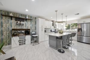 una cucina con armadi bianchi e un'isola con sgabelli da bar di Villa Hanna a Lighthouse Point