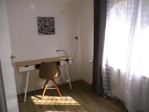 a desk and a chair in a room with a window at Ferienwohnung am Hotel "Mein Bergblick" in Goslar