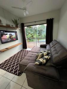 een woonkamer met een bank en een groot raam bij Casa Brisa do Siriú in Garopaba