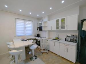 een keuken met witte kasten en een tafel en stoelen bij CityPark BnB in Pristina