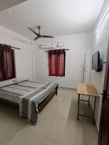 ein Schlafzimmer mit Bett und Deckenventilator in der Unterkunft Beevis Gray, Kazhakuttoom in Kaniyapuram