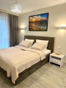 ein Schlafzimmer mit einem Bett mit einem Bild an der Wand in der Unterkunft Apartament RELAX in Pogorzelica