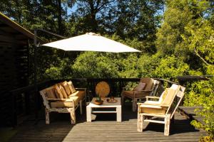 una terraza de madera con sillas y sombrilla en Estero El Claro Hotel y Cabañas, en Pucón