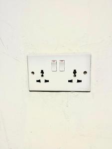 a lightswitch on a white wall with arrows on it at Reef Nungwi House in Nungwi