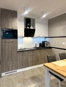 eine Küche mit Holzschränken und einem Holztisch in der Unterkunft Apartament RELAX in Pogorzelica