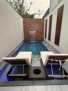 una piscina con due sedie e un tavolo di Casa estrada 6 a Bertioga