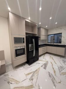 una cucina con pavimenti in marmo bianco ed elettrodomestici neri di Casa estrada 6 a Bertioga