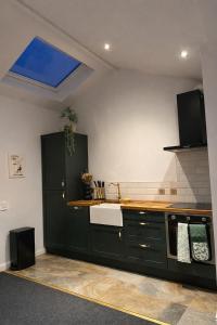 a kitchen with black cabinets and a sink and a window at Cosy Coach House - Belfast in Belfast