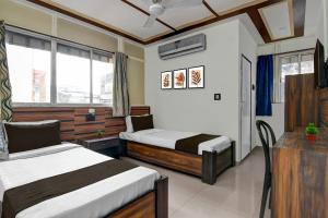 ein Hotelzimmer mit zwei Betten, einem Tisch und einem Fenster in der Unterkunft Hotel O Galaxy Inn in Ballygunge