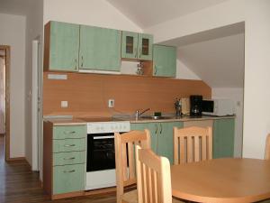 a kitchen with green cabinets and a wooden table at Kisiovi Apartment in Devin