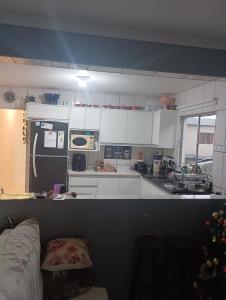 una cucina con mobili bianchi e un frigorifero nero di Casa ap a Bertioga