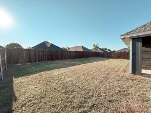einen Hinterhof mit einem Holzzaun und einem Hof in der Unterkunft Beautiful 3BD 2B - Weatherford - Same Day Bookings in Weatherford