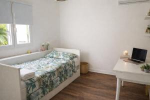 a bedroom with a bed and a desk with a laptop at La Grippiere in Petit-Bourg +2 photos