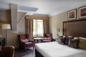a hotel room with a bed and two chairs at Nutfield Priory Hotel & Spa in Redhill +73 photos