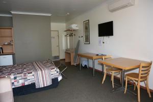 a room with a bed and a desk and a table at Forbes Victoria Inn in Forbes