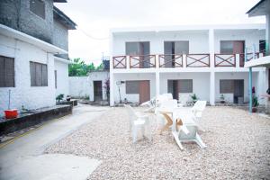 un patio con sillas blancas y una mesa frente a un edificio en Spice Garden Lodge B&B, en Zanzíbar