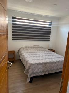 una piccola camera da letto con un letto e una finestra di Hermosos Departamentos en La Serena a La Serena