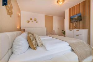 ein Schlafzimmer mit einem großen weißen Bett und Kissen in der Unterkunft Ferienwohnung Goldkind in Ostseebad Kölpinsee