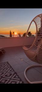 een rotan stoel zittend op een balkon met de zonsondergang bij Casa del Sol in Altea