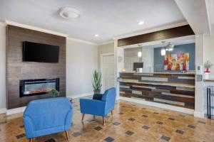 a living room with two blue chairs and a fireplace at SureStay Hotel by Best Western Terrell in Terrell