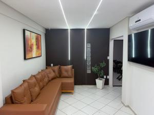 a living room with a brown couch and a flat screen tv at Hotel Portal do Sertao in Feira de Santana