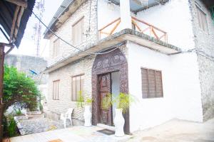 een wit gebouw met een houten deur en een plant bij Spice Garden Lodge B&B in Zanzibar City