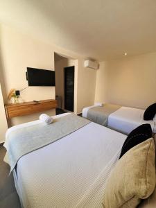 Una habitación de hotel con dos camas y un lavabo. en Aruma Suites, en Playa del Carmen