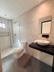 Un baño blanco con inodoro y lavabo. en Aruma Suites, en Playa del Carmen 12 fotos más