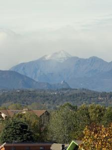 a snow covered mountain in the distance with houses and trees at La casa di Alice in Orbassano