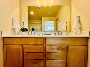 een badkamer met een wastafel en een grote spiegel bij Organ Mountain Loft 3BR 3 Steps into Golf Course in Las Cruces +34 foto's