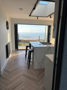 a kitchen and dining room with a view of the ocean at The New 2 Plas Morolwg in Aberystwyth