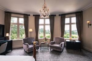 a bedroom with a bed and two chairs and a chandelier at Rookery Hall Hotel & Spa in Nantwich