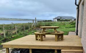 een picknicktafel en bank op een houten terras bij Beachcroft Cottage in Aird Tong