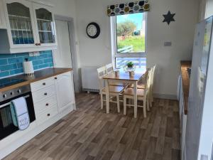 een keuken met een tafel en stoelen en een raam bij Beachcroft Cottage in Aird Tong