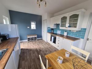 een keuken met witte kasten en een houten tafel bij Beachcroft Cottage in Aird Tong