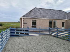 een huis met een blauw hek ervoor bij Beachcroft Cottage in Aird Tong +12 foto's