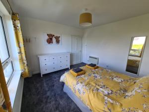 een slaapkamer met een bed, een ladekast en een raam bij Beachcroft Cottage in Aird Tong
