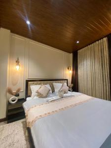 1 dormitorio con 1 cama blanca grande y techo de madera en Denka's, en Darjeeling