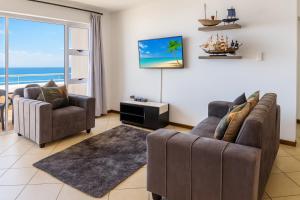 ein Wohnzimmer mit zwei Sofas und Blick auf das Meer in der Unterkunft 606 L'esclaier Cabanas - Seaside Paradise in Amanzimtoti