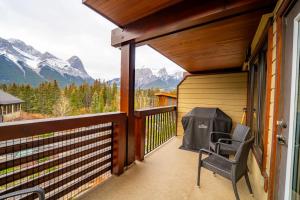 a balcony with a table and a chair and mountains at Rundle Range Retreat Lux Mtn View Condo near dt in Canmore